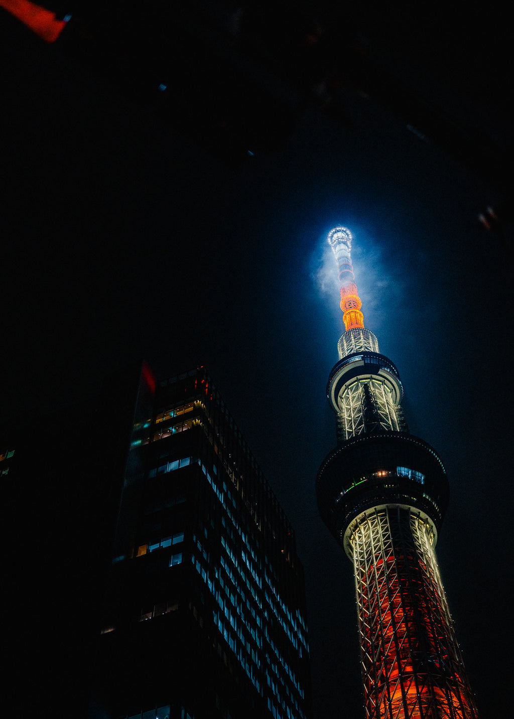 Tall tower illuminated at night with a dark sky background - primary