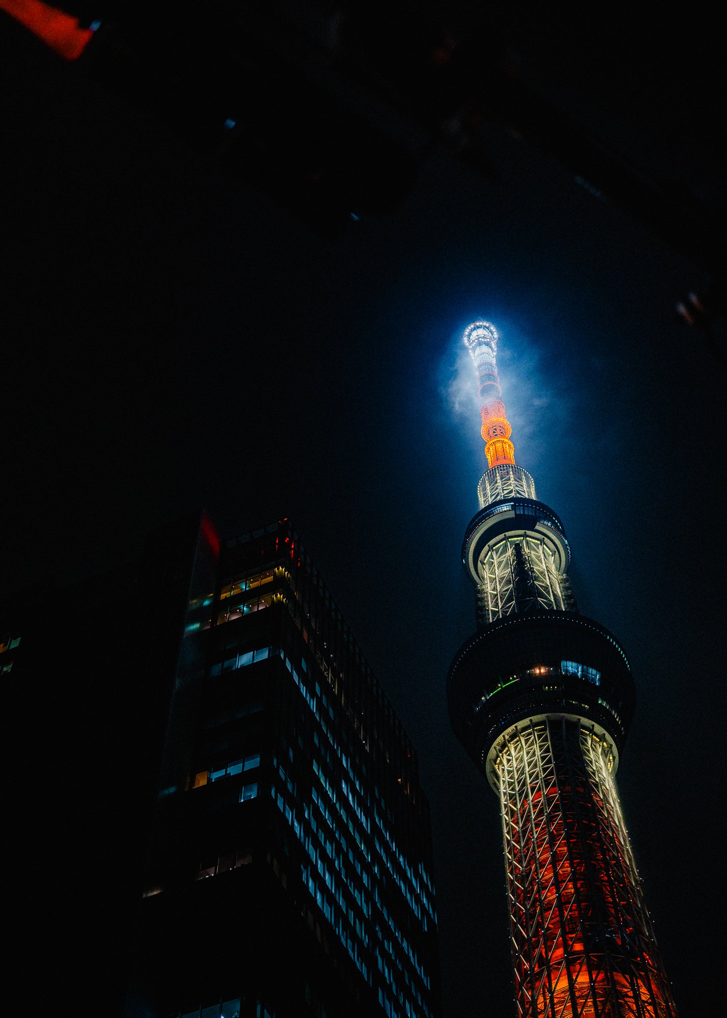 Tall tower illuminated at night with a dark sky background - primary