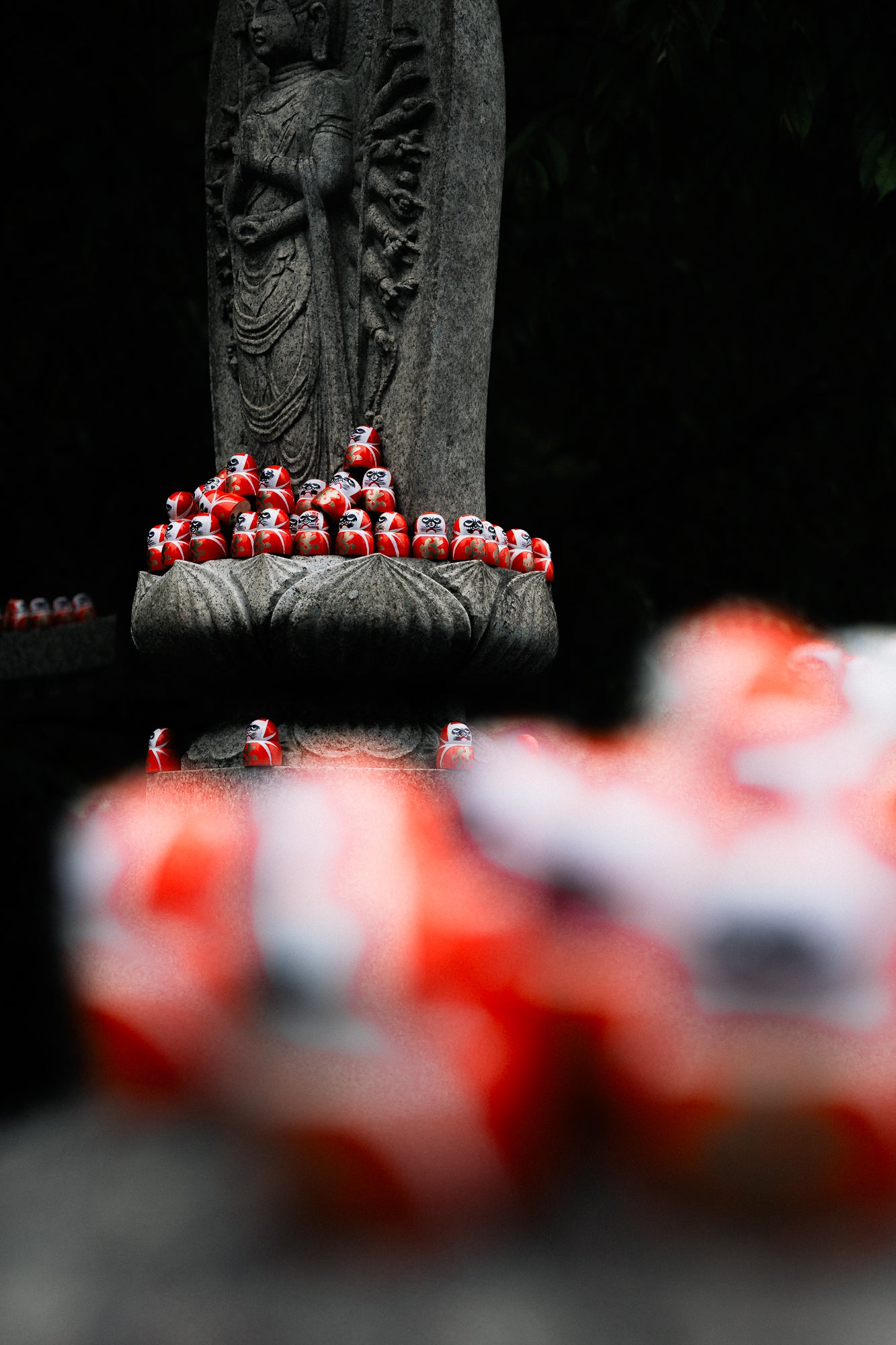 Statue with red figurines around it on a black background - primary