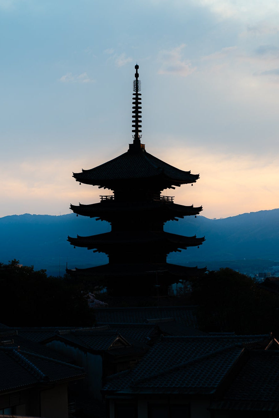 Silhouette of a pagoda against a mountainous landscape during sunset - primary